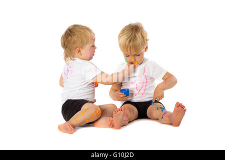 Gemelli fratelli giocando con la vernice, isolato su bianco. Foto Stock