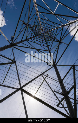 Guardando in alto nel frame di un traliccio di elettricità con cielo blu chiaro overhead. Foto Stock