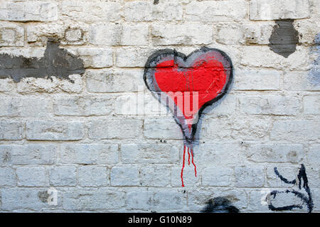 Cuore rosso graffiti su un dipinto di bianco muro di mattoni Foto Stock