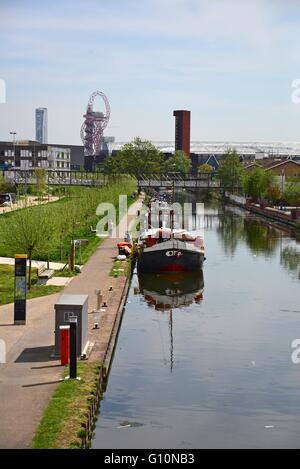Canali in barca sul fiume Lea, Hackney Wick, con la regina Elisabetta Olympic Park in background, East London, Regno Unito Foto Stock