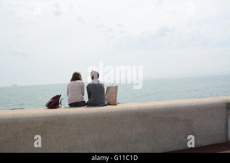 Portsmouth, Regno Unito. Il 7 maggio 2016. Una giovane coppia sedersi e parlare contro la splendida cornice del canale. Credito: Marc Ward/Alamy Live News Foto Stock