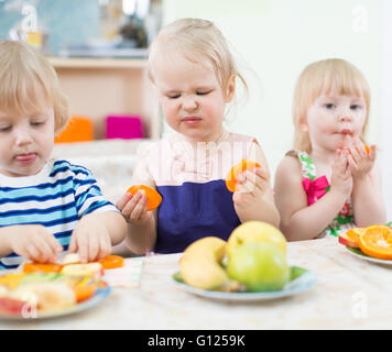Bambini divertenti mangiare frutta nella scuola materna Foto Stock