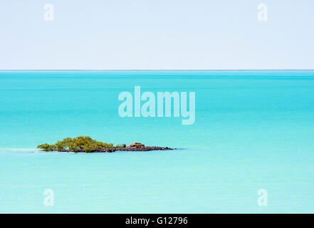 Piccolo promontorio roccioso coperto di mangrovie nelle acque azzurre del mare in Roebuck Bay, Broome, Kimberley, Australia occidentale, Australia Foto Stock
