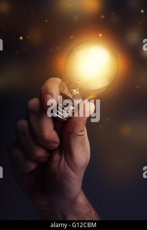 Energia creativa e la potenza delle nuove idee, la mano che tiene la luce della lampadina, dai toni rétro immagine, il fuoco selettivo. Foto Stock