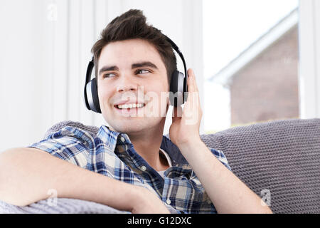 Giovane uomo ascoltare musica su cuffie senza fili Foto Stock
