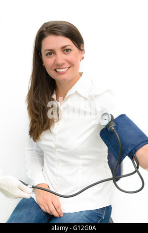 Bella giovane donna utilizzando la misurazione della pressione sanguigna sfigmomanometro del dispositivo Foto Stock