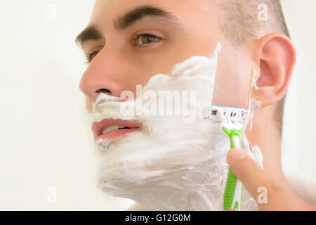 Giovane uomo la rasatura con lama di rasatura Foto Stock