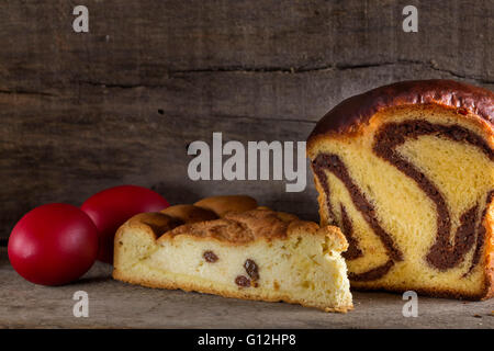 Torte rumeno Cozonac con purè di dadi e Pasca con formaggio e uvetta e colorati tradizionali uova di pasqua Foto Stock