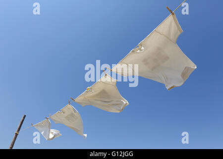 Lavanderia bianco appeso sul stendibiancheria contro il cielo blu Foto Stock