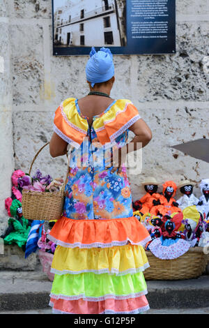 Un venditore di fiori che indossano il costume tradizionale guarda al panno bambole in vendita nella Plaza de la Catedral, l'Avana Vecchia Havana, Cuba Foto Stock