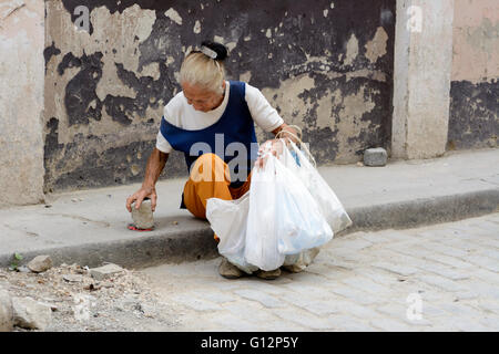 Una donna anziana raccoglie lattine da vendere per riciclaggio da strade di l'Avana Vecchia Havana, Cuba Foto Stock