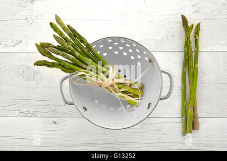 Freschi asparagi verdi in scolapasta sul vecchio sfondo di legno Foto Stock