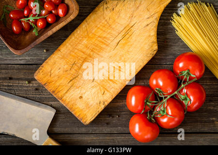 Vista dall'alto il cibo della cucina italiana ingredienti su legno rustico sfondo. Pomodori, spaghetti, olio di oliva e insalata di rucola Foto Stock