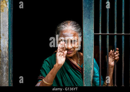 Signora indiana sventolare attraverso una entrata sbarrata al di fuori del tempio Kapaleeshwarar, Mylapore, Chennai, nello Stato del Tamil Nadu, India Foto Stock
