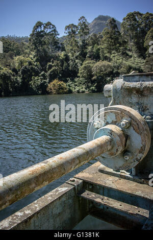Età heavy-duty macchinari della gravità alimentata diga sul fiume Mattupetty con tranquilla sul lago e alberi dietro Foto Stock
