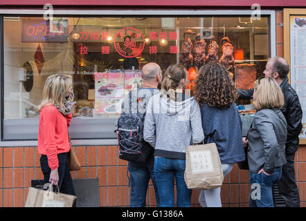 Gli acquirenti della finestra scegliere la loro cena cinese a Londra in area di Chinatown Foto Stock