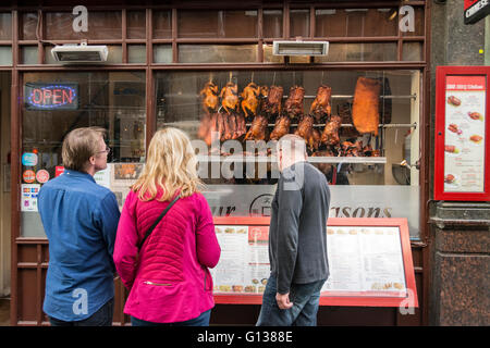 Gli acquirenti della finestra scegliere la loro cena cinese a Londra in area di Chinatown Foto Stock