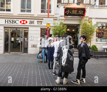 La gente in coda al di fuori della HSBC punto di contanti macchina su Gerrard Street, Londra, WC2, Regno Unito Foto Stock