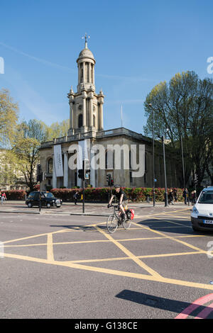 Un ciclista passa la chiesa della Santa Trinità costruzione su una trafficata Marylebone Road a Londra, Regno Unito Foto Stock