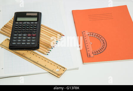 Il concetto di apprendimento illustrato con una calcolatrice e matite su uno sfondo di un foglio di carta millimetrata Foto Stock