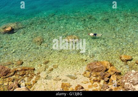 Vista pittoresca su dalmata spiaggia rocciosa in Croazia con nuoto uomo Foto Stock