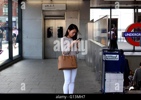 Donna vicino alla stazione di King Cross utilizzando il suo telefono cellulare Foto Stock