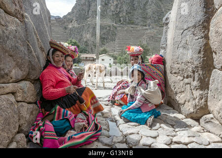 Ollantaytambo, Perù - 18 dicembre 2014: le donne e i bambini in peruviano tradizionale pausa vestiti da posa con turisti Foto Stock