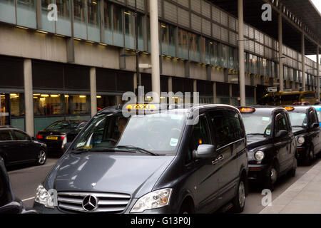 Una coda di London Black Cab taxi in fila in corrispondenza di una stazione di taxi in attesa di raccogliere passeggeri vicino a Kings Cross Station con per noleggio illuminato di luce Foto Stock