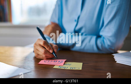 Creative giovane donna disegni Disegno in ufficio sulla colorata memo pad come si siede alla sua scrivania , Vista ravvicinata delle sue mani un Foto Stock