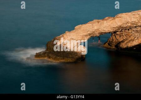Grotte marine costa rocciosa in Cape Creco, nei pressi di Ayia Napa, Cipro. Sotto la grotta, due persone sono la pesca. Foto Stock