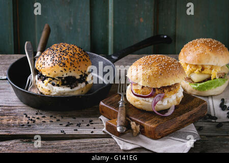 Tre fatti in casa hamburger vegetariano con patate dolci, nero di riso e fagioli rossi, servita sul tagliere di legno sopra il vecchio tavolo in legno Foto Stock