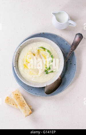 Terrina di asparagi bianchi minestra in crema con i germogli di piselli e toast, servito con una brocca di latte bianco su sfondo di pietra. Lay piatto Foto Stock