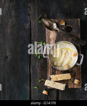 Vintage coppa in alluminio con asparagi bianchi minestra in crema con i germogli di piselli e toast, servita sul tagliere di legno su legno vecchio Foto Stock