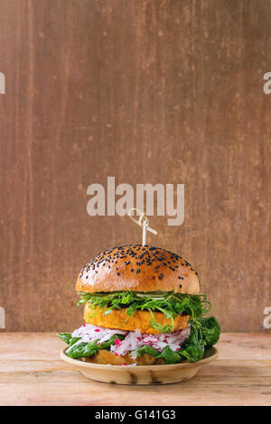 In casa veggie patata dolce burger con rafano fresco e i germogli di pisello servito sulla piastra di argilla in legno sfondo a trama. Foto Stock