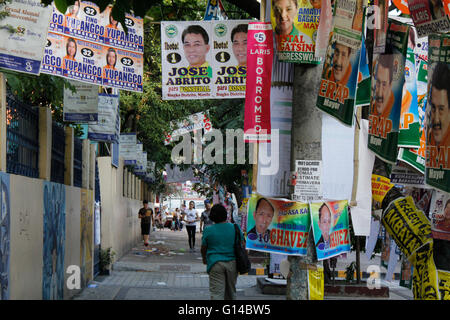 Manila, Filippine. 08 Maggio, 2016. I Filippini a piedi passato i banner della campagna dei candidati per le elezioni come si vede nei pressi di una scuola pubblica a Manila nelle Filippine alla vigilia del giorno delle elezioni. Cinquanta-quattro milioni di filippini gli elettori registrati sono voce ai centri di polling domani, 9 Maggio a votare per le elezioni presidenziali e vice presidential post, i successori di amministrazione corrente del presidente filippino Benigno Aquino III. Le elezioni generali includono anche i senatori e deputati del parlamento, e locali e provinciali di posizioni. © Marlo Cueto/Pacific Press/Alamy Live News Foto Stock