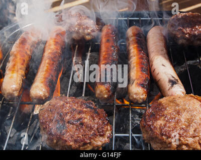 Salsicce e hamburger di essere cucinati su un barbecue Foto Stock