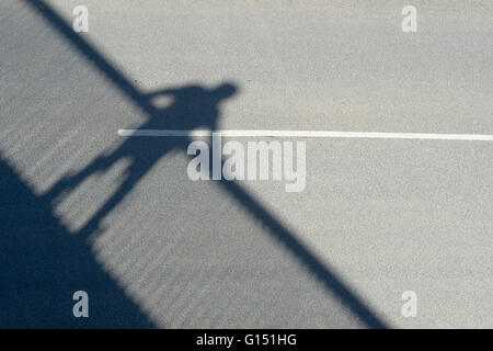 Ombra di un uomo su un ponte a piedi su una strada Foto Stock