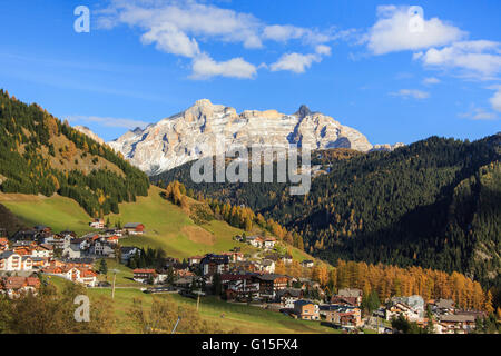 Boschi colorati telaio il villaggio e le cime più alte in autunno, Passo Gardena, Alto Adige, Trentino Alto Adige, Italia, Europa Foto Stock