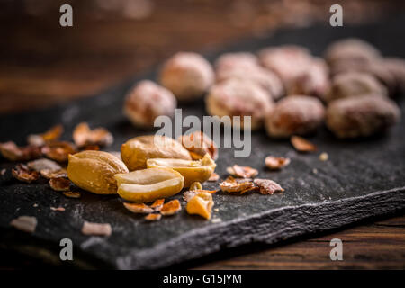 Arrosto e arachidi salate su nero ardesia board Foto Stock