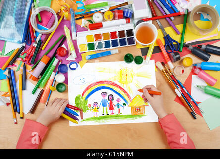 La famiglia sul prato con arcobaleno e casa di disegno per bambini, vista dall'alto le mani con matita foto di pittura su carta, artwork workplace Foto Stock