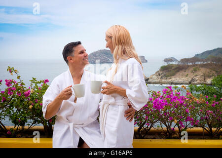 Coppia caucasica in bianco accappatoi un caffè sulla terrazza di un oceano fron home Foto Stock