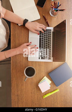 Vista superiore verticale di colpo di mani femminili lavorando su un computer portatile. Donna fare business da casa. Foto Stock