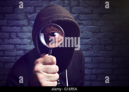 Incappucciati hacker con lente di ingrandimento, hacker di internet e la sicurezza online concetto. Foto Stock