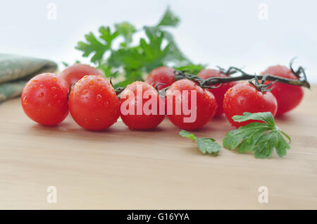 Pomodori giacciono su una superficie in legno, luce naturale e bokeh di fondo. Foto Stock