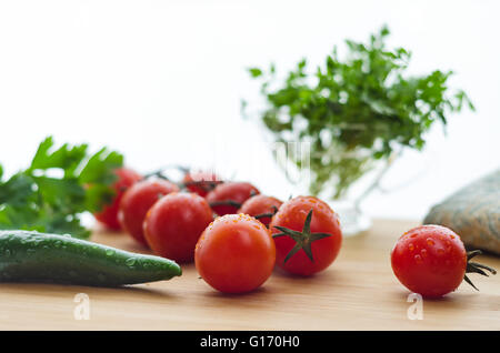 Pomodori e cetrioli su una superficie in legno, luce naturale, bokeh di fondo. Foto Stock