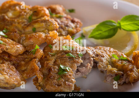 Maiale fritto del cervello con limone e erbe su piastra bianca Foto Stock