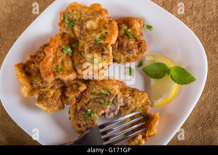 Maiale fritto del cervello con limone e erbe su piastra bianca Foto Stock