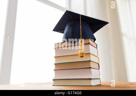 Close up di libri e mortarboard sul tavolo di legno Foto Stock