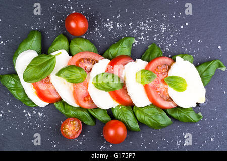 Italiana fresca insalata caprese con mozzarella, pomodoro e basilico sul grigio scuro dello sfondo di ardesia Foto Stock
