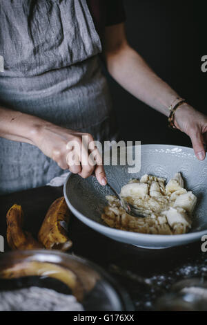 Una donna è la miscelatura delle banane per essere utilizzato in un pane alla banana ricetta di ciambella. Foto Stock